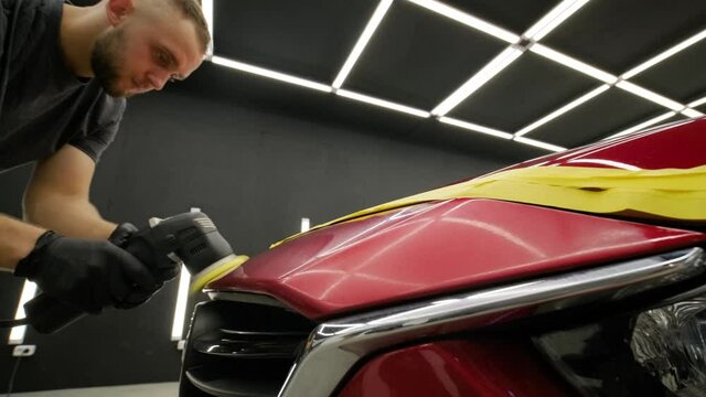 Worker polish a red car. Car detailing - Men are using machinery car polishers maintenance to remove marks repair according to the surface of the car's paint before contin