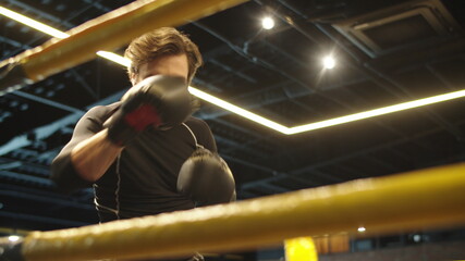 Focused sport man boxing at gym. Male boxer doing punches on boxing ring