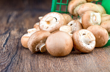 Champignon mushrooms poured from a basket on the table.