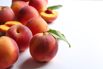 Fresh ripe peaches and green leaves on white background, closeup. Space for text