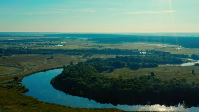 Aerial view of sunrise with a blue sky above river Desna, Ukraine. Drone flies up above beautiful morning landscape while  sunrise. Drone is flying over tranquil summer landscape.