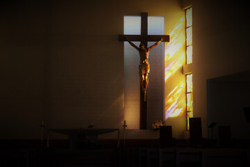 Naklejka premium The crucifixion of Jesus on the cross in the temple, illuminated by the sun through the stained glass windows.