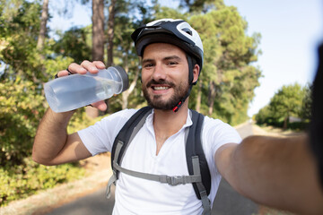 sport cyclist drinking water and taking selfie