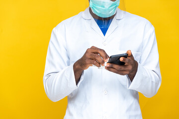 man wearing a lab coat, and face mask and shield cleaning the surface of his phone