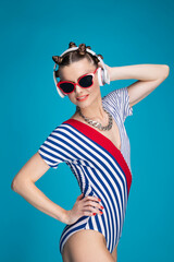 Beautiful stylish female model with bright makeup listening to music and smiling. Closeup Portrait on bright blue background