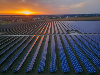 Aerial drone view into large solar panels at a solar farm at bright sunset. Solar cell power plants.