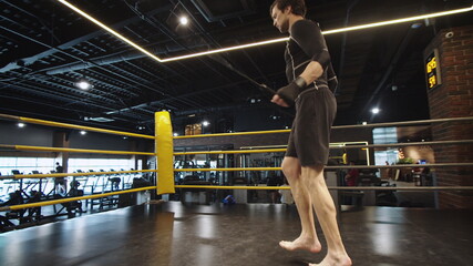Energetic sport man making jumps at gym. Male boxer exercising in sport club
