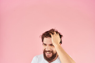 Bearded man in white t-shirt gesturing with hands facial expression close up pink background