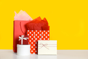 Shopping bags and gift boxes on yellow background. Space for text