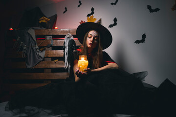 a mysterious brunette in a witch costume holds her hat with her hand