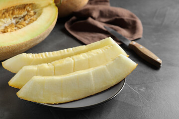 Slices of delicious honey melon on black table