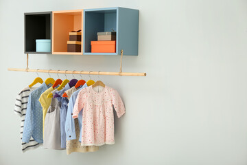 Rack with different clothes on light background. Space for text