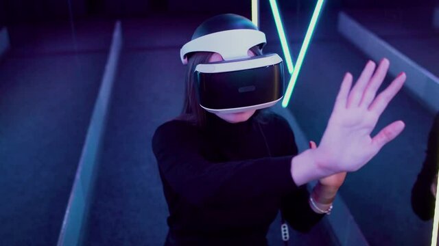 Girl wears VR glasses in a neon room A woman joins virtual reality