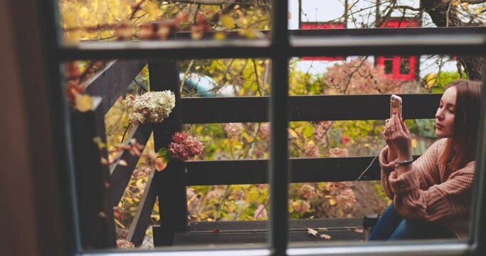 Woman Using Smartphone In Fall Outdoors. SLOW MOTION. Beautiful female with cell phone taking pictures of autumn aesthetic still life, social networking. Technology in everyday lockdown life. 