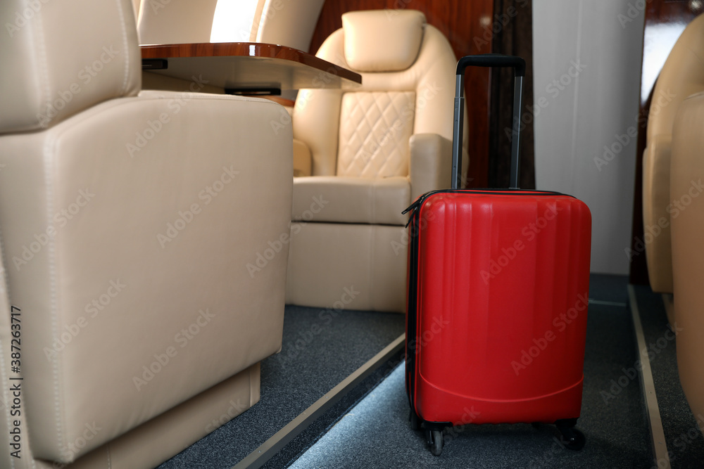 Wall mural Airplane cabin with red suitcase. Air travel