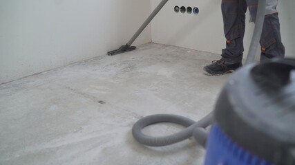 Close-up of thoroughly vacuums the concrete floor. A worker vacuums the floor from industrial...