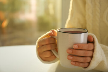Woman holding elegant cup at table indoors, closeup