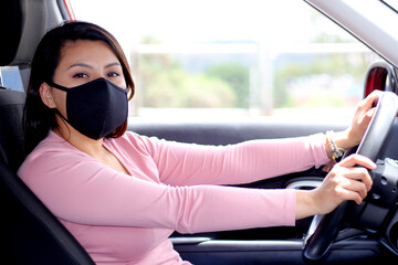 latin woman driver with protection mask in vehicle interior, new normal when driving