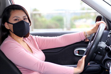 latin woman driver with protection mask in vehicle interior, new normal when driving