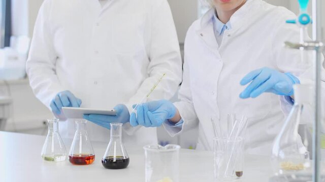 Chemist working with hemp CBD oil and tablet in laboratory
