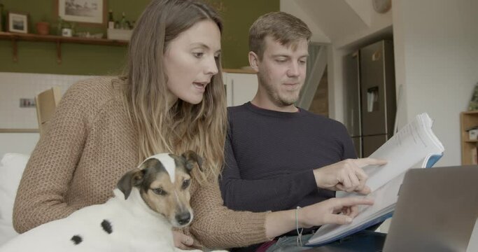 Couple at home looking at finance on sofa with dog on lap