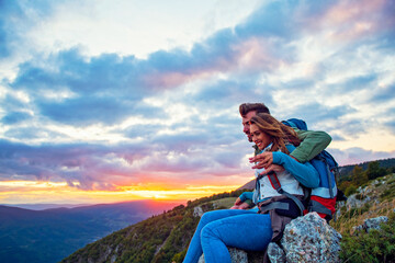Young Couple Sitting On Top Of Mountain