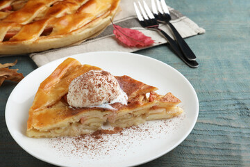 Slice of traditional apple pie with ice cream served on blue wooden table, closeup