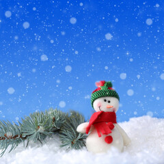 Naklejka na ściany i meble Cute snowman and fir tree branch on snow against blue background, bokeh effect