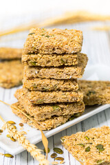Multigrain Cereal Crunchy Squares Bars with Pumpkin Seeds on Wooden Background. Selective focus.