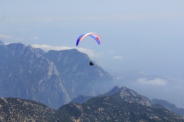 Paraglider flying above Tahtali Mountain in Kemer, Antalya Region, Turkey with Taurus Mountains in...