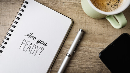 Are you ready? Flat lay. Work area with notepad, pen, cell phone and a cup of coffee. 