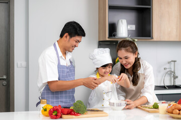 Young Asian love family are preparing food dinner on table in the kitchen which father and mother teaching daughter to cooking food on the day at home..