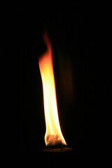 A fire burning in an oil lamp on a black background