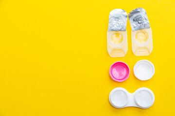 Open package of contact lenses and container with contact lense on a yellow background copy space.