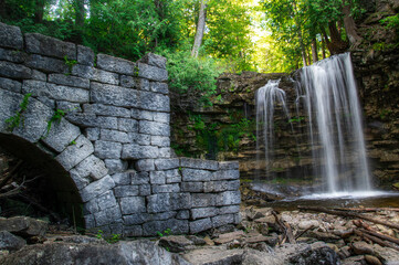 A long exposure shot of Hilton Falls near Milton, Ontario, cascading down into a pool below, with the ruins of an old mill in the foreground.