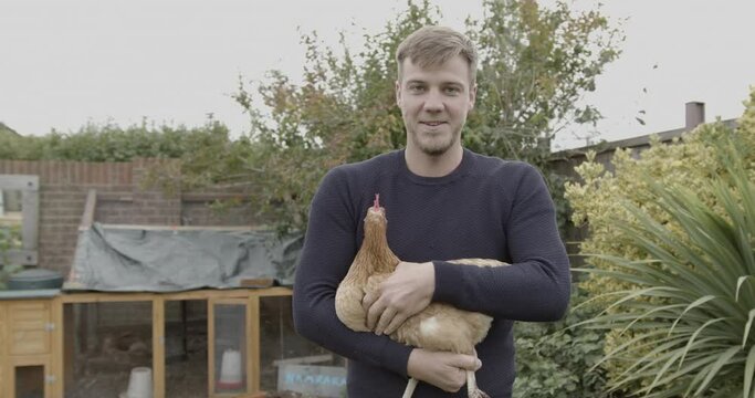 Portrait of adult Man holding Hen Chicken in Garden at home, simple living