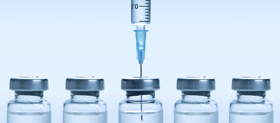 Medical syringe with a needle and a bollte with vaccine.