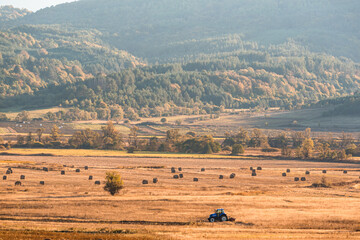 Lonely tractor harvest hay field crop stubble golden yellow orange autumn mountain background massive bulgaria technology machine agriculture