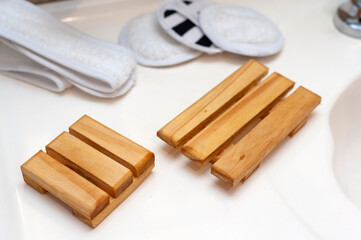Modern and ecological wooden soap holder on bathroom countertop, along with reusable cleaning pad.