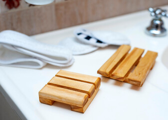 Modern and ecological wooden soap holder on bathroom countertop, along with reusable cleaning pad.