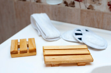 Modern and ecological wooden soap holder on bathroom countertop, along with reusable cleaning pad.