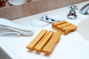 Modern and ecological wooden soap holder on bathroom countertop, along with reusable cleaning pad.