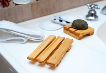 Modern and ecological wooden soap holder on bathroom countertop, along with reusable cleaning pad.