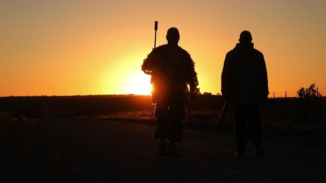 Slow motion of hunter and tracker walking out of the sun on an African Savanna hunt