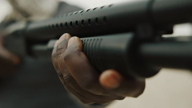 Close up shot of a man pumping a shotgun