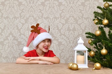  A boy in a carnival striped red and white cap with deer horns closed his eyes and made a merry face.