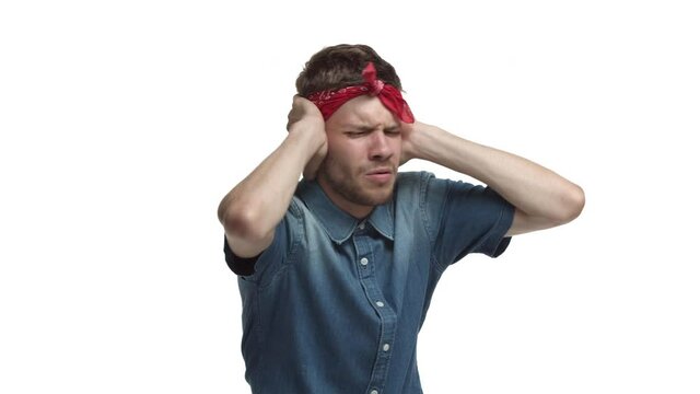 Video of handsome bearded man with red bandana, ignoring you, shut ears with hands and shaking head in denial, refusing something bad, standing displeased over white background