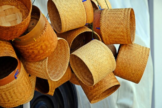Bamboo wicker sticky rice baskets hanging for sale in the market.