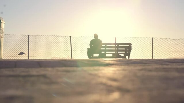 4K man walking towards a banch at the beach