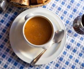 Appetizing tomato soup cooked in meat broth served in white tureen.